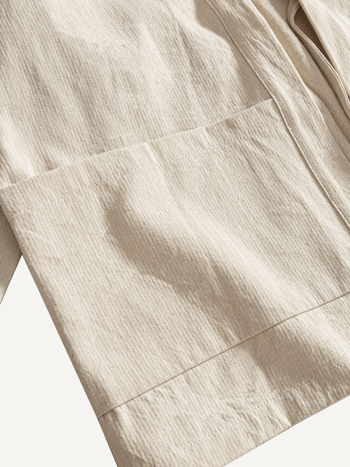 Close-up of generous front patch pocket on beige cotton kimono cardigan jacket
