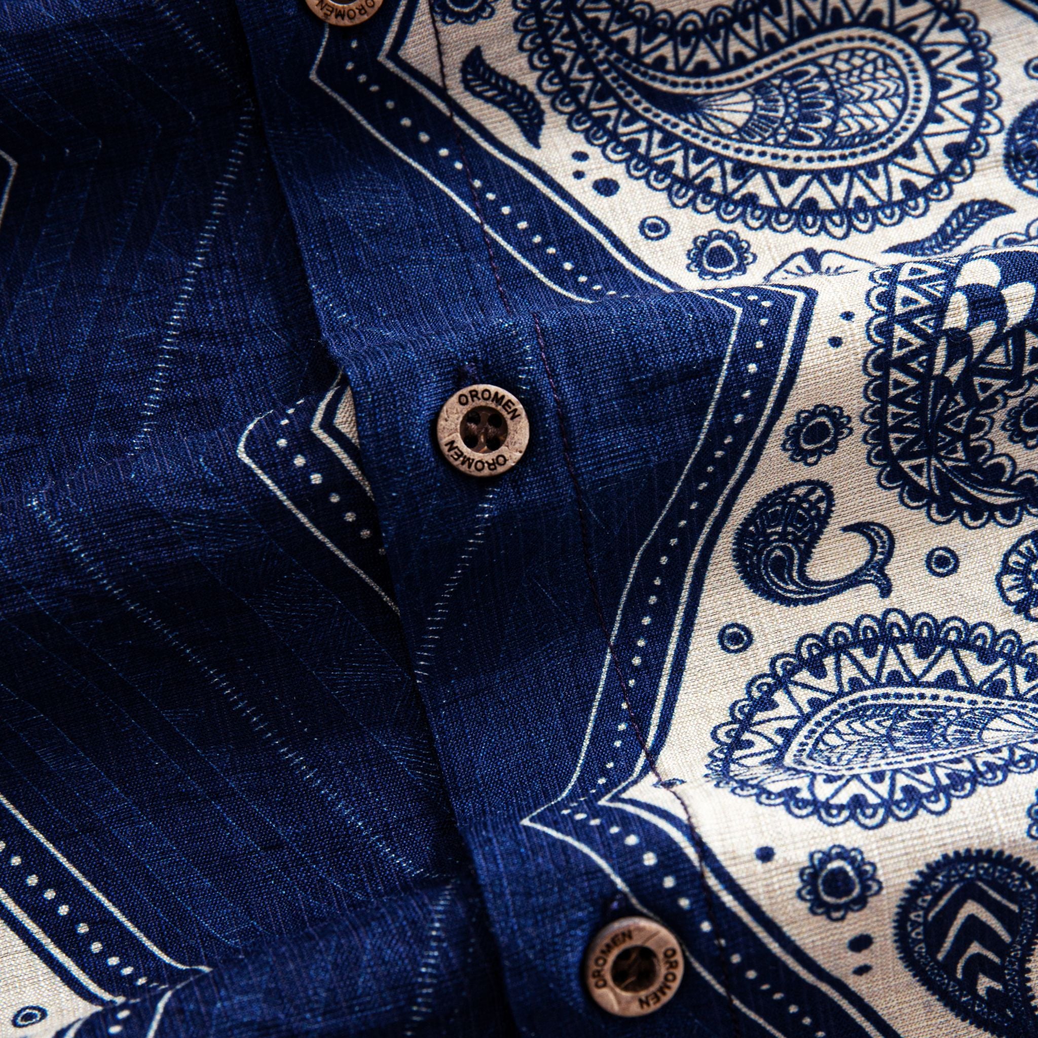 OROMEN Paisley Bandana shirt branded coconut button close-up against navy blue body and off-white paisley print placket