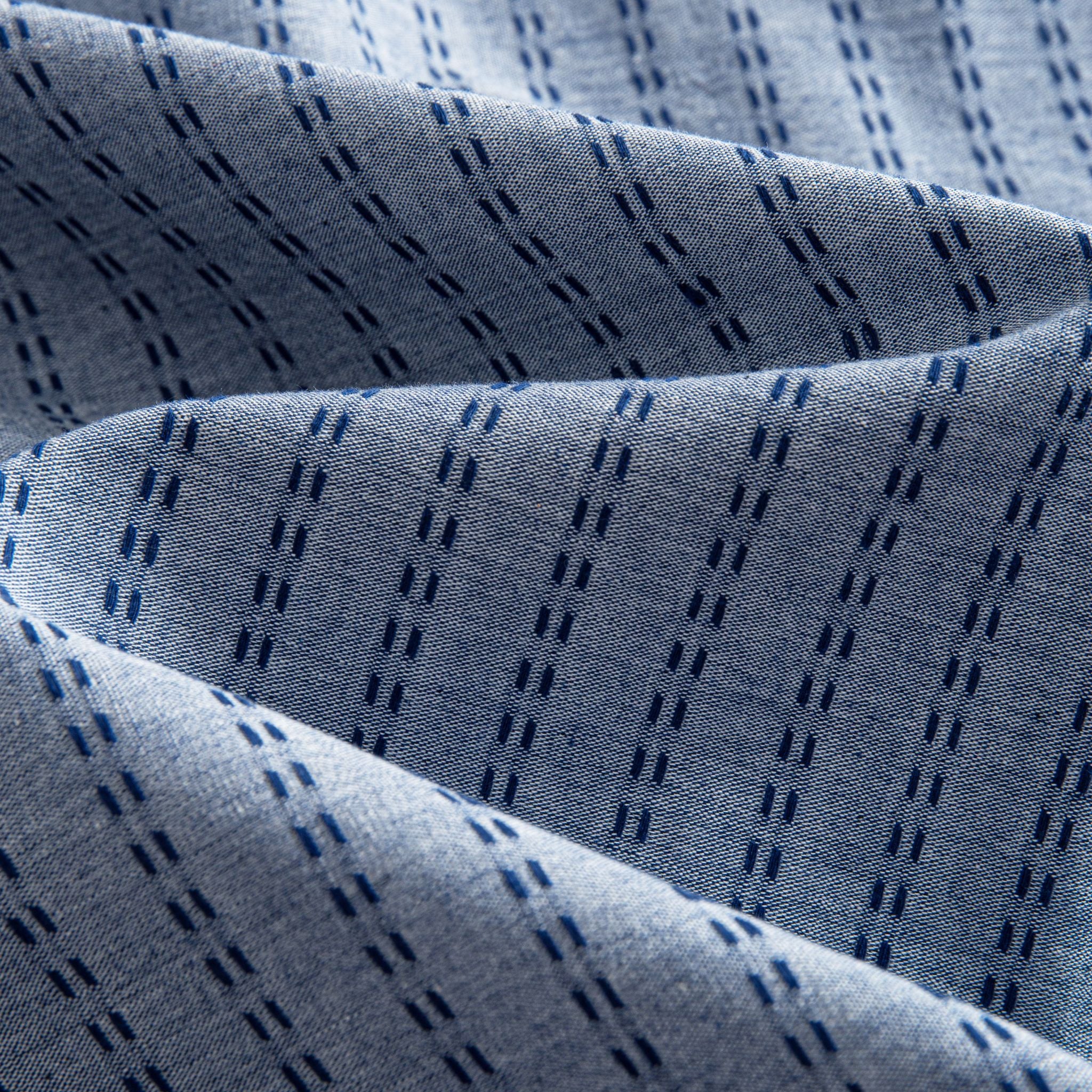 OROMEN Sashiko Chambray shirt fabric close-up, navy Sashiko dash texture on washed chambray blue cotton