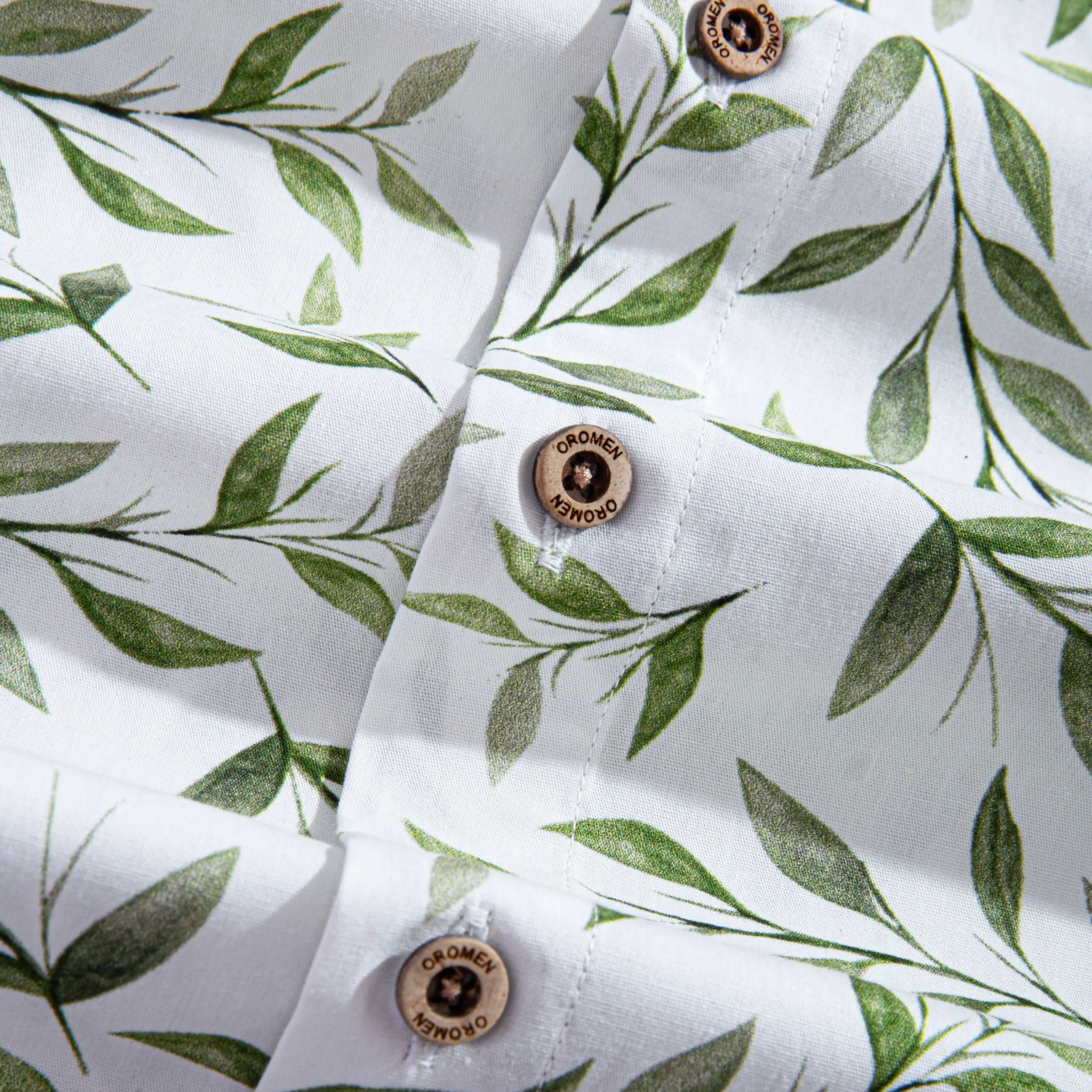 OROMEN engraved coconut buttons and green willow leaf print detail on Willow Bough Hawaiian shirt