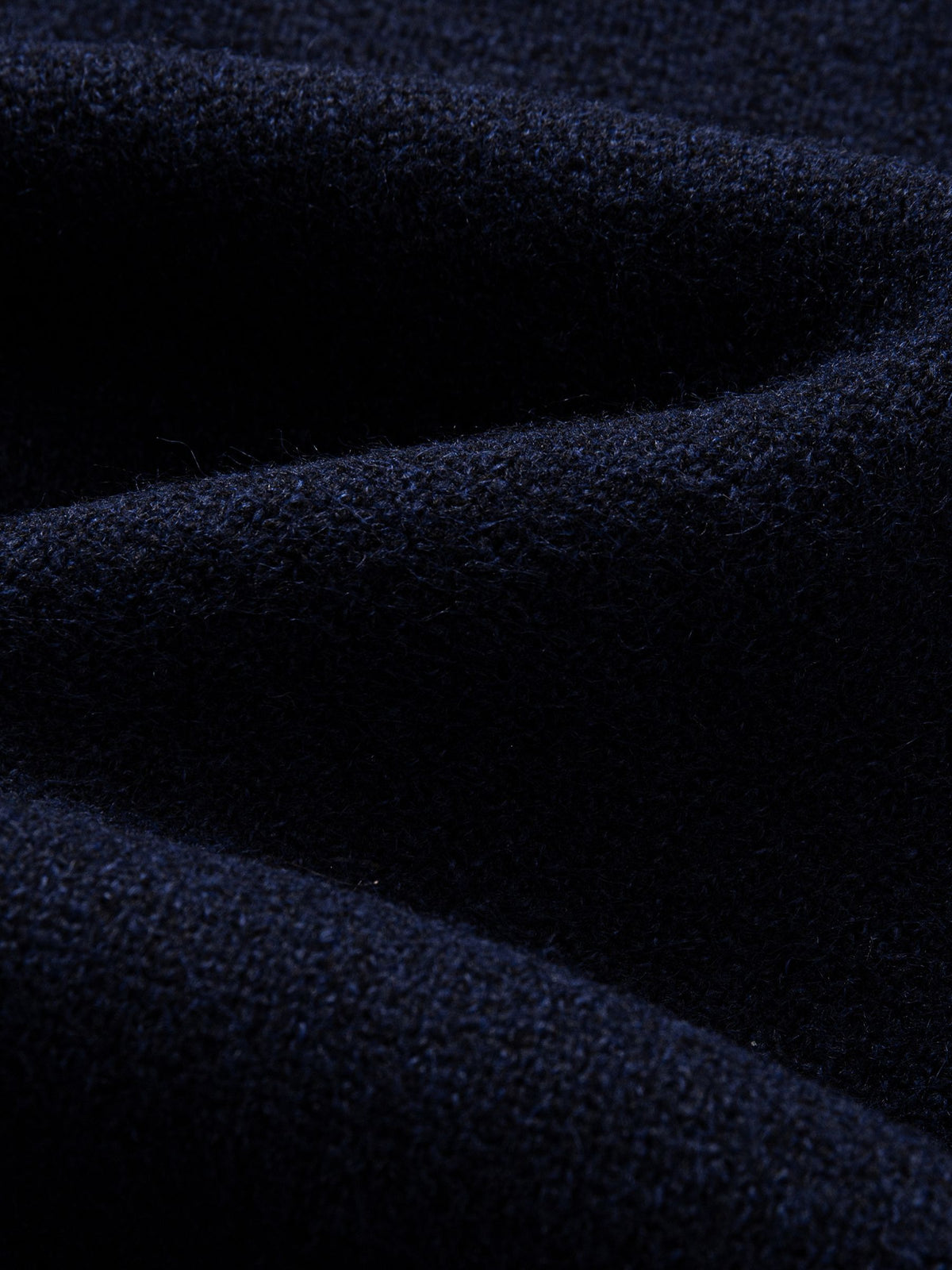 Texture detail of soft stretch-knit polyester blend fabric on navy contrast collar polo sweater