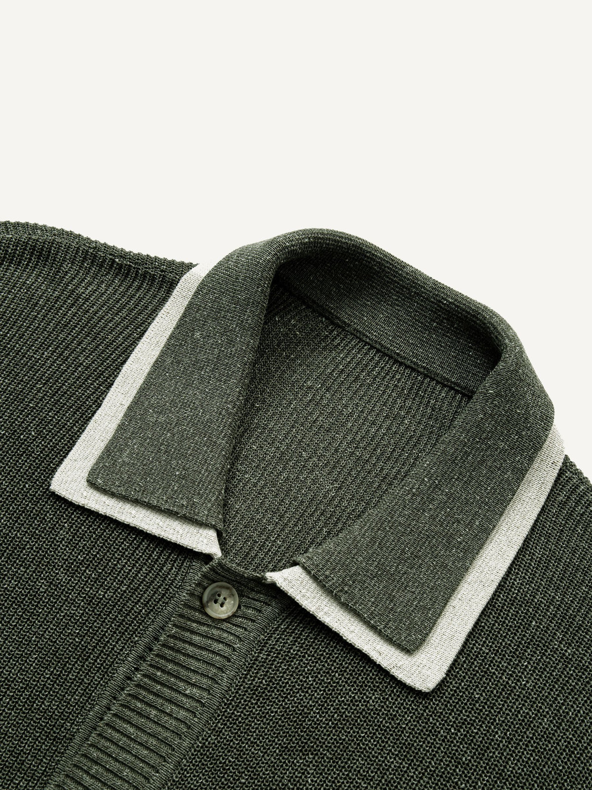 Close-up of contrast white trim on olive green polo collar knit cardigan
