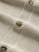 Close-up of contrasting front buttons on oatmeal polo collar sweater cardigan
