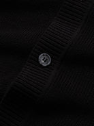 Close-up of front button closure along the placket on black polo knit cardigan