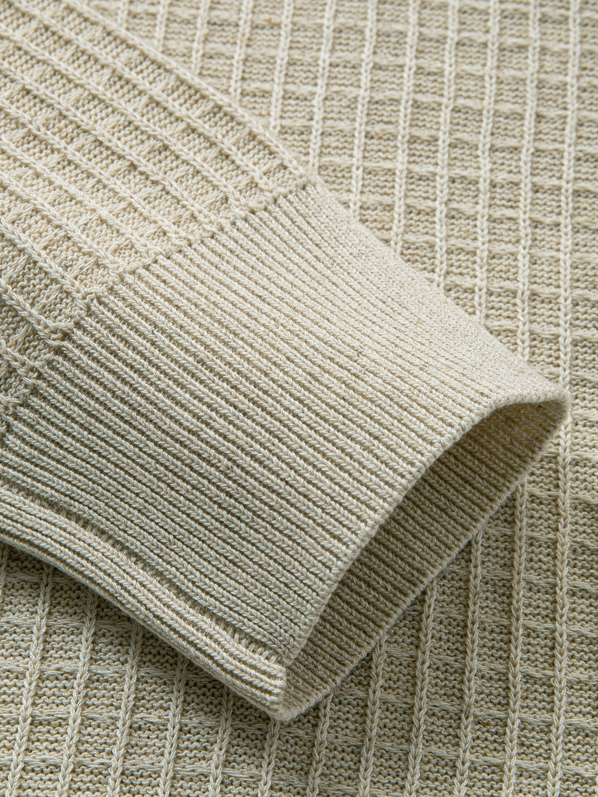 Close-up of ribbed knit elastic sleeve cuffs on beige button-down sweater