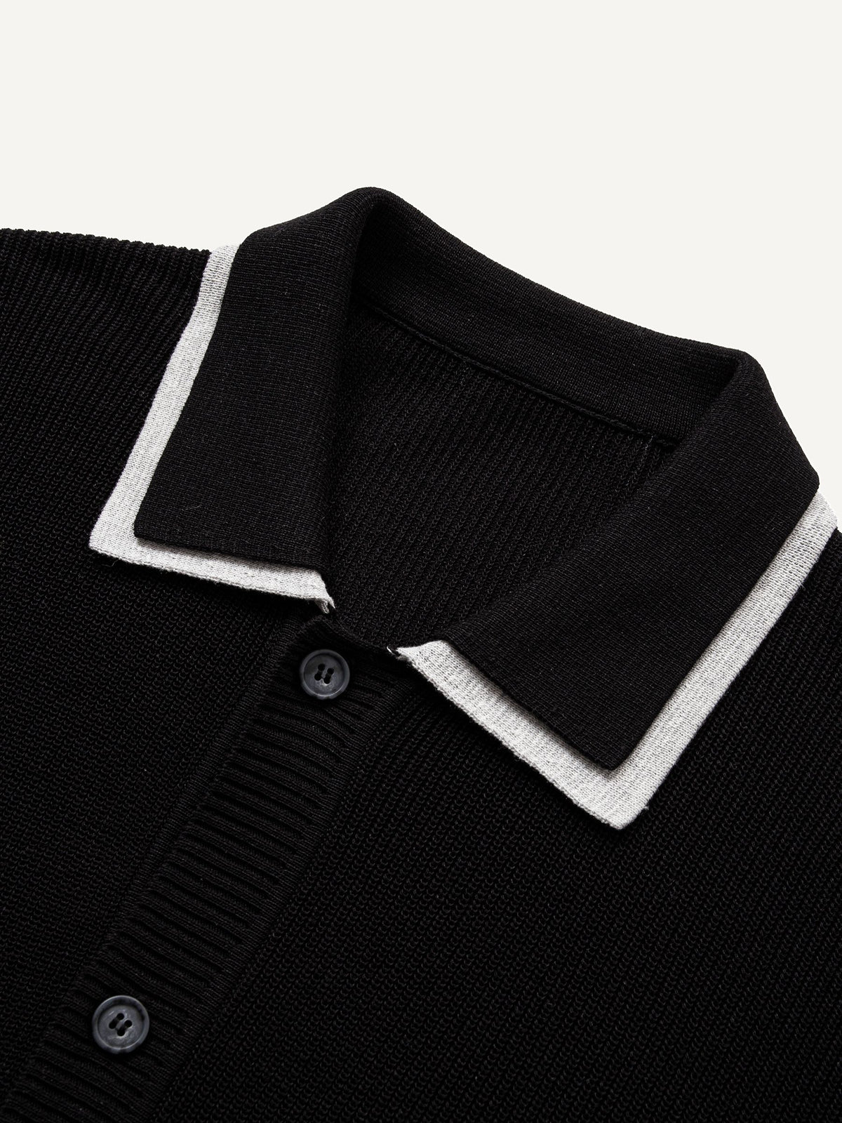 Close-up of sharp white contrast polo collar on black fine-ribbed knit cardigan