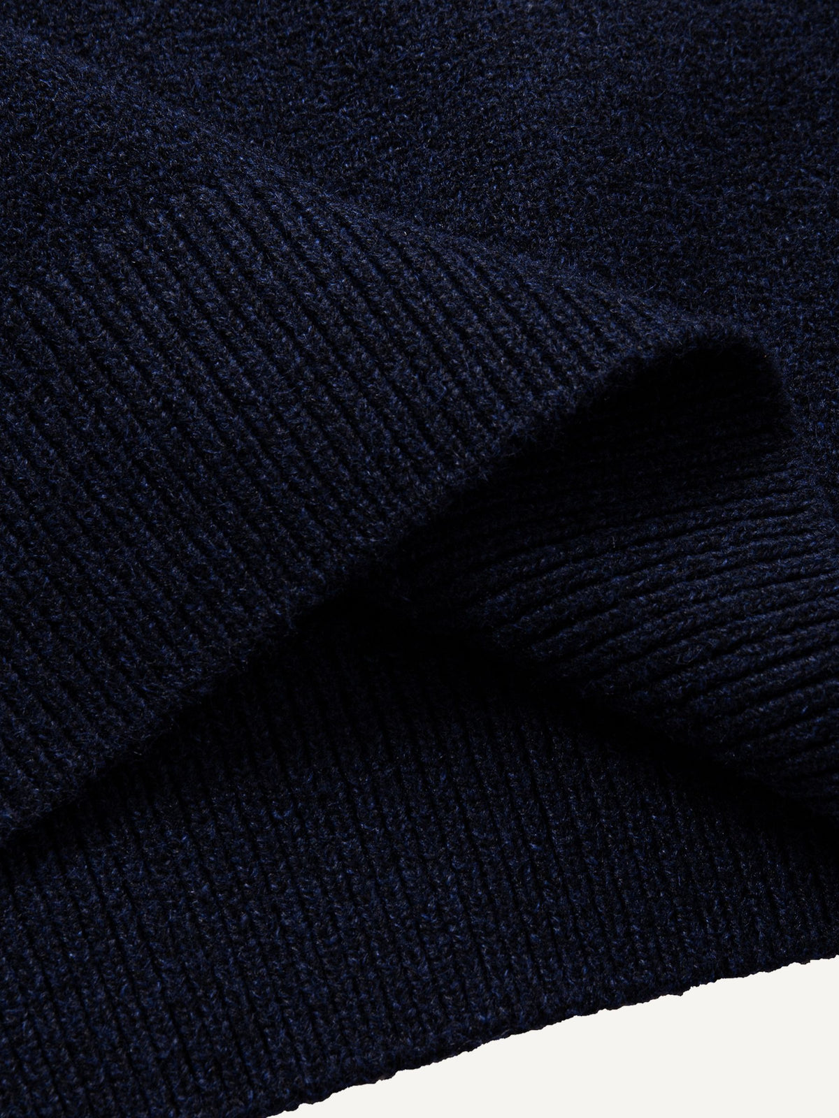 Close-up of the clean ribbed hem on navy stretch-knit polo sweater