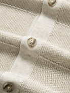 Close-up of tonal front button closure along the placket on oatmeal knit polo cardigan