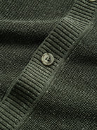 Close-up of vintage button closure along the front placket on olive knit cardigan