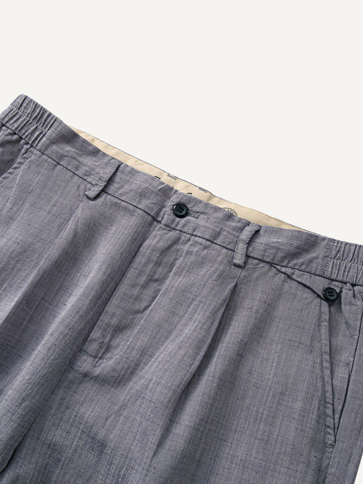 Front waistband detail of OROMEN Pleated Relaxed Fit Linen Trousers with double pleats
