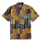 OROMEN Ajrakh Mosaic Hawaiian shirt front flat lay showing full allover patchwork block layout with paisley, sun circles, folk birds and floral motifs in navy, amber, slate blue and burgundy