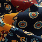 OROMEN Ajrakh Mosaic shirt fabric close-up showing concentric sun circles, paisley and floral patchwork panels in navy, amber and burgundy on 100% premium cotton
