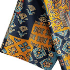 OROMEN Ajrakh Mosaic shirt sleeve detail showing multi-color Ajrakh patchwork motifs including paisley, floral and geometric blocks in navy, amber and slate blue cotton