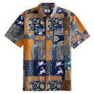 OROMEN Aviary Patchwork Hawaiian shirt front flat lay showing full patchwork block layout with peacocks, folk birds and botanical motifs in navy blue and amber orange