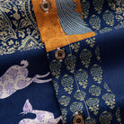 OROMEN Aviary Patchwork shirt branded coconut button close-up against peacock and botanical patchwork panels with amber orange placket