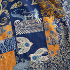 OROMEN Aviary Patchwork shirt chest pocket close-up showing patchwork panel arrangement with peacock and botanical motifs in navy blue and amber orange