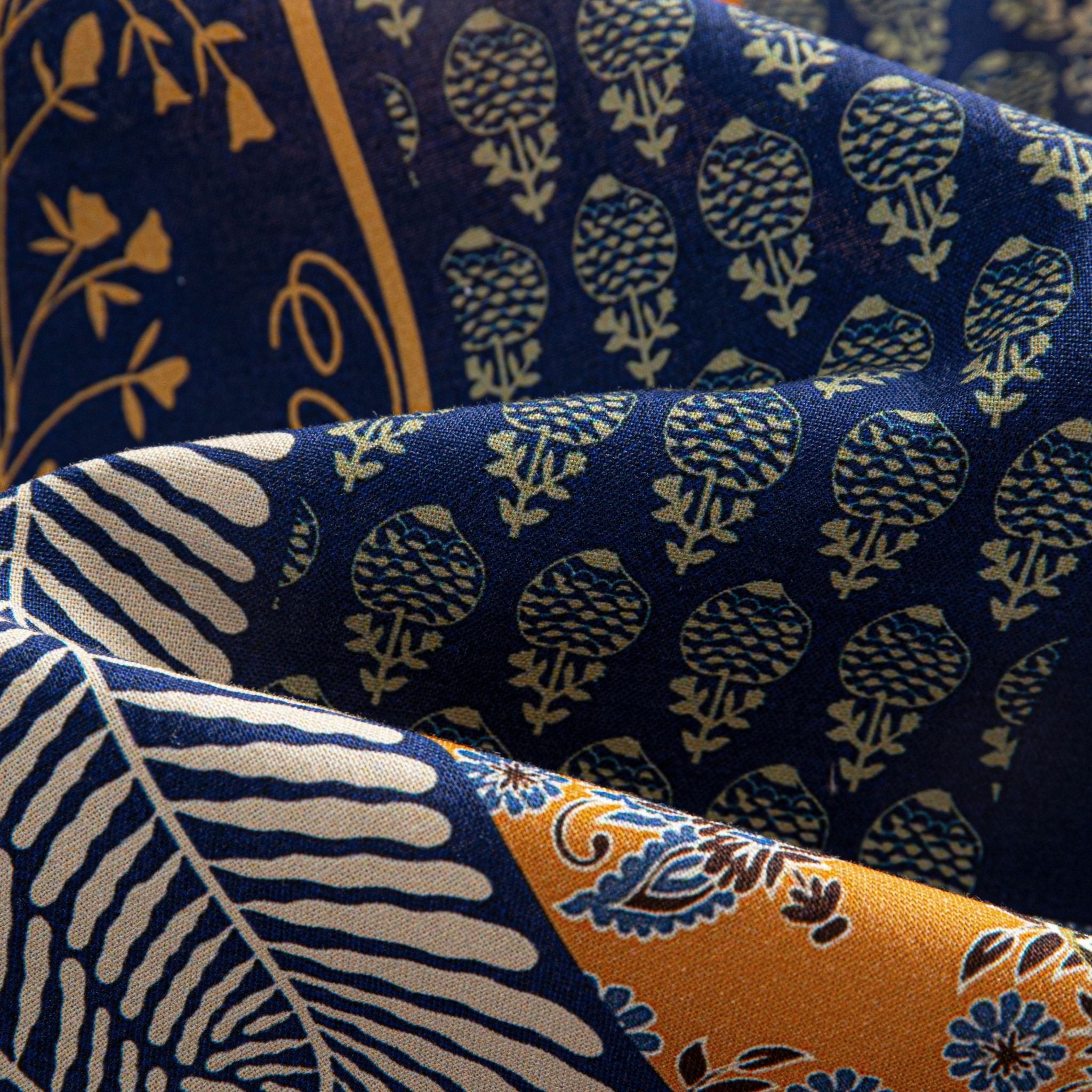OROMEN Aviary Patchwork shirt fabric close-up showing fern leaf and circular tree motif patchwork panels on navy blue 100% premium cotton