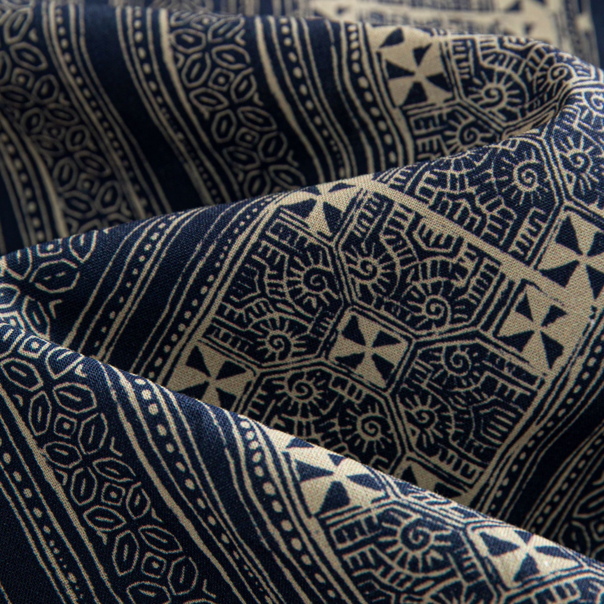 OROMEN Indigo Batik shirt fabric close-up, eight-pointed star and spiral motifs in navy and off-white cotton