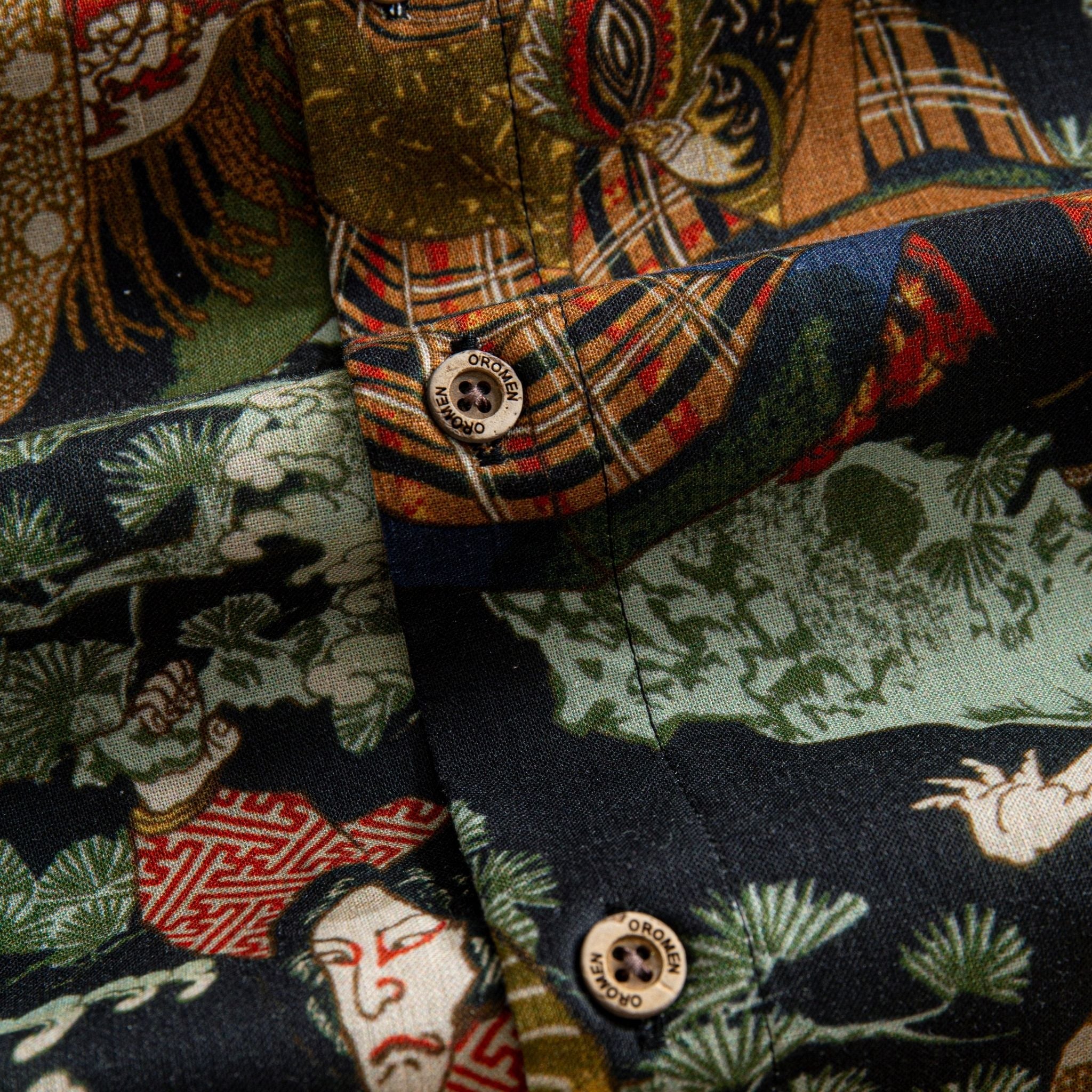 OROMEN Kabuki Warriors shirt branded coconut button close-up against Kabuki figure and pine tree print on dark navy ground
