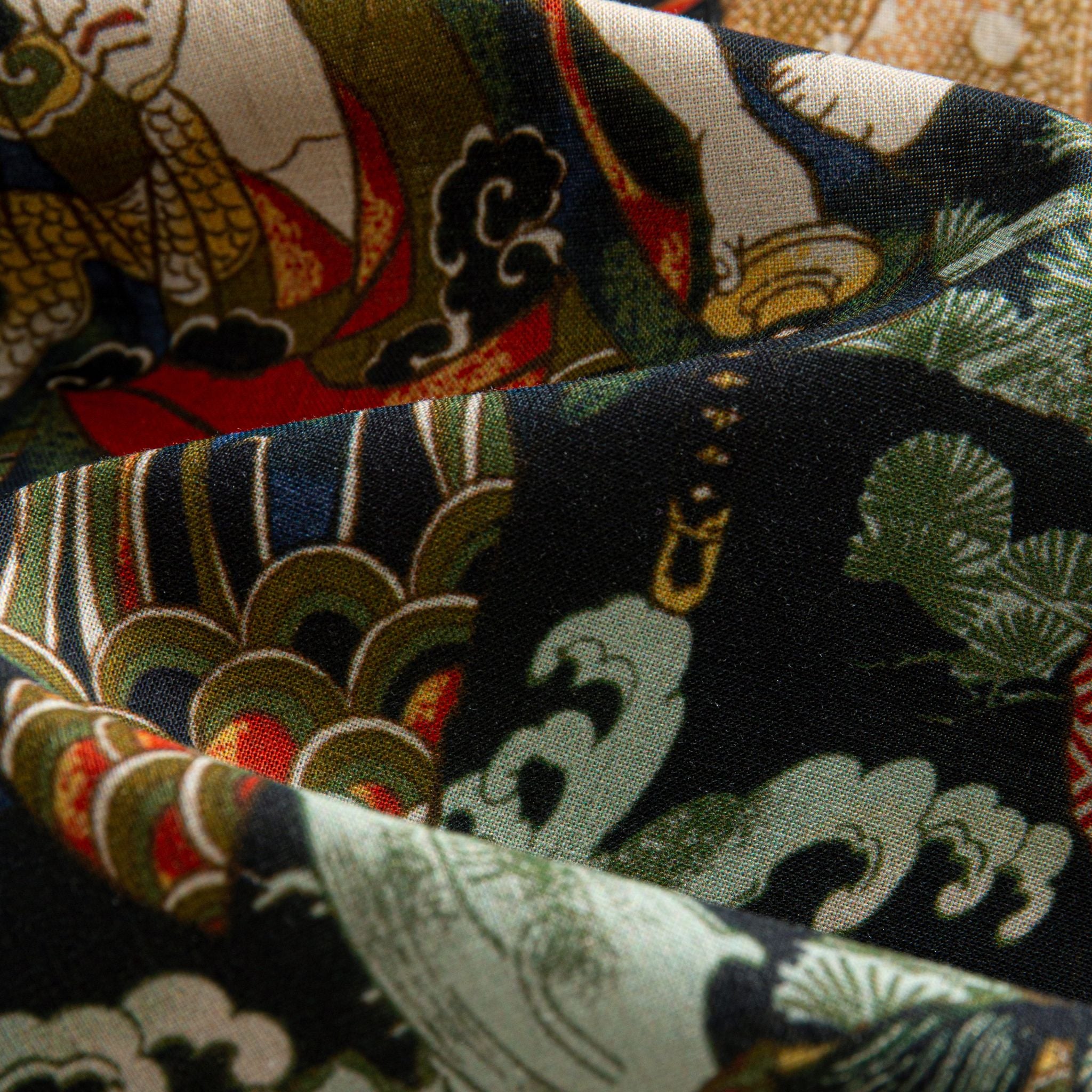 OROMEN Kabuki Warriors shirt fabric close-up showing Japanese cloud waves, pine trees and gold decorative motifs on 100% premium cotton