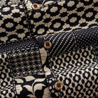OROMEN Noir Patchwork shirt branded coconut button close-up against leopard spot, diamond heart grid and polka dot patchwork panels in black and off-white