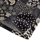 OROMEN Noir Patchwork shirt side vent detail showing polka dot, snowflake geometric and floral patchwork blocks with double needle stitching in black and off-white
