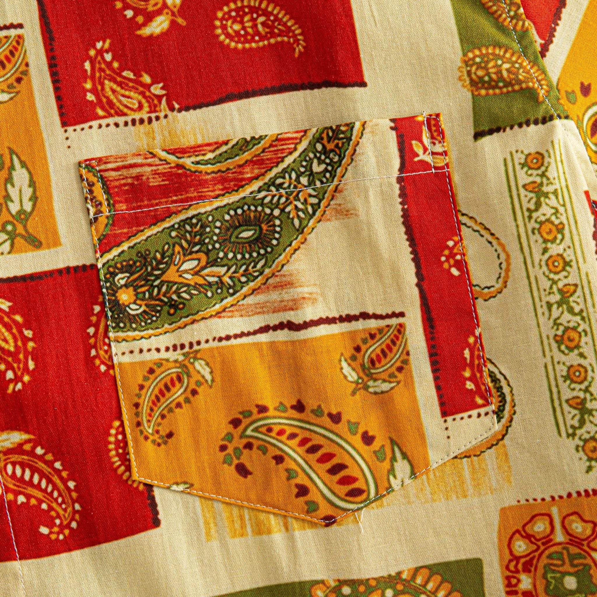 OROMEN Rajasthan Paisley shirt chest pocket close-up showing paisley patchwork print continuing across pocket seam in crimson, amber and olive on cream ground