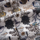OROMEN Reef Atlas Hawaiian shirt – engraved coconut buttons close-up with marine coral and fish print background