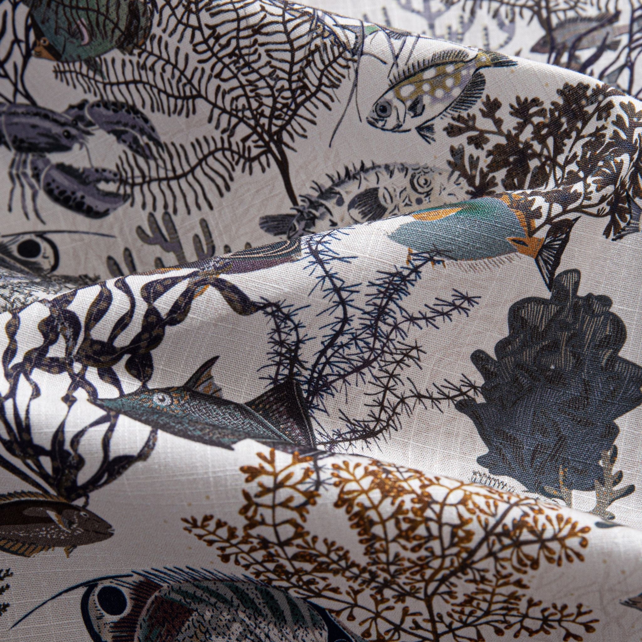 OROMEN Reef Atlas Hawaiian shirt – folded fabric detail showing lobster, tropical fish and coral naturalist print on white cotton