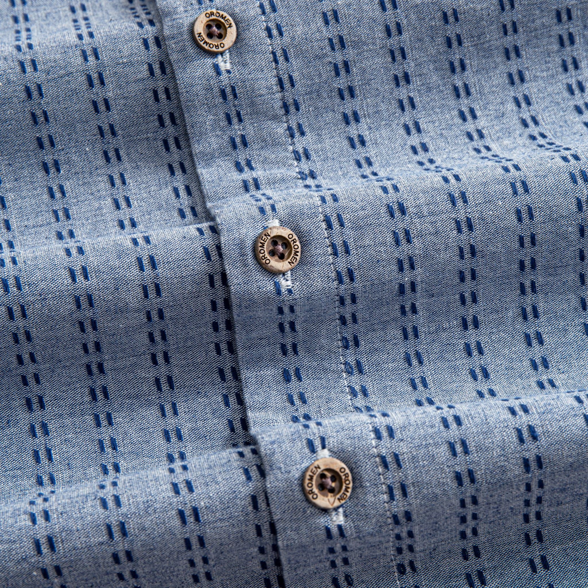 OROMEN Sashiko Chambray shirt branded coconut button close-up, navy Sashiko stitch on chambray blue