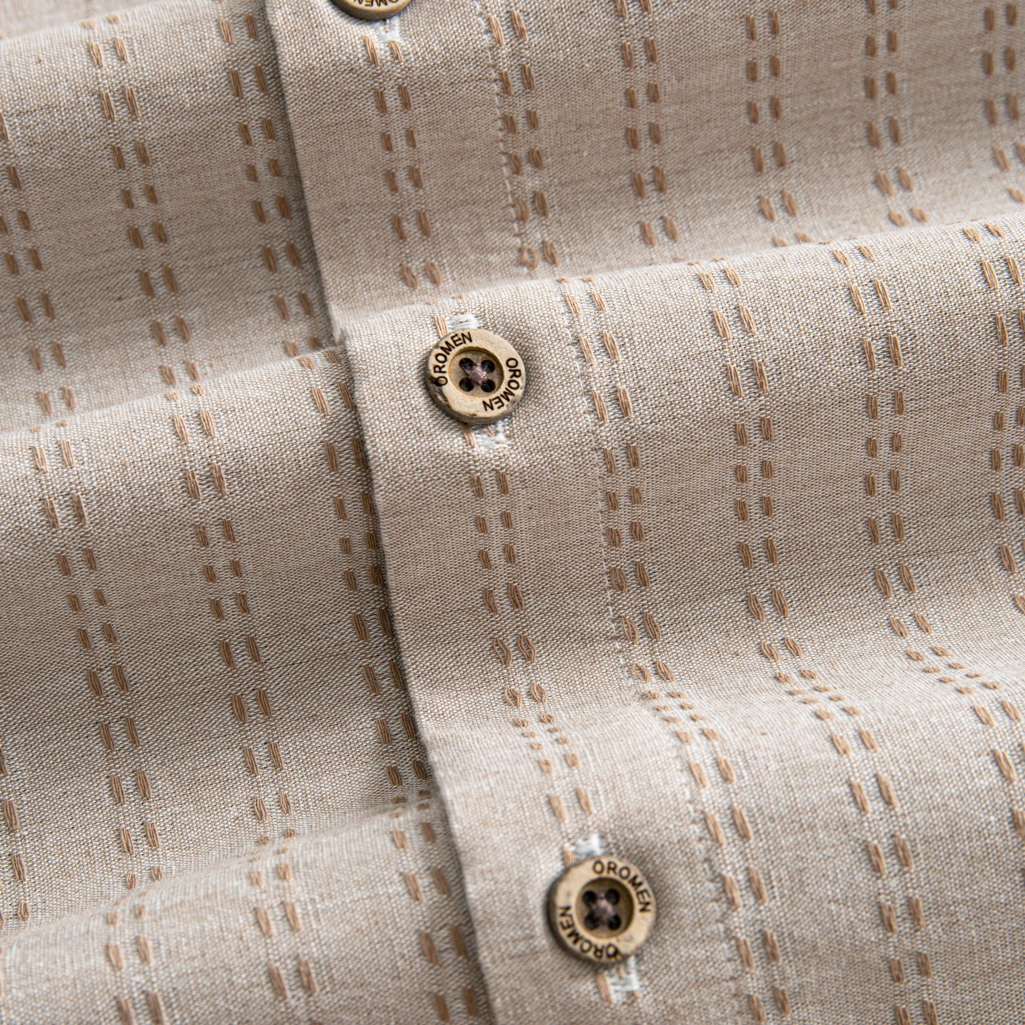OROMEN Sashiko Natural shirt branded coconut button close-up, tan Sashiko stitch on oatmeal cotton