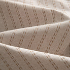 OROMEN Sashiko Natural shirt fabric close-up, warm tan Sashiko dash texture on natural oatmeal cotton