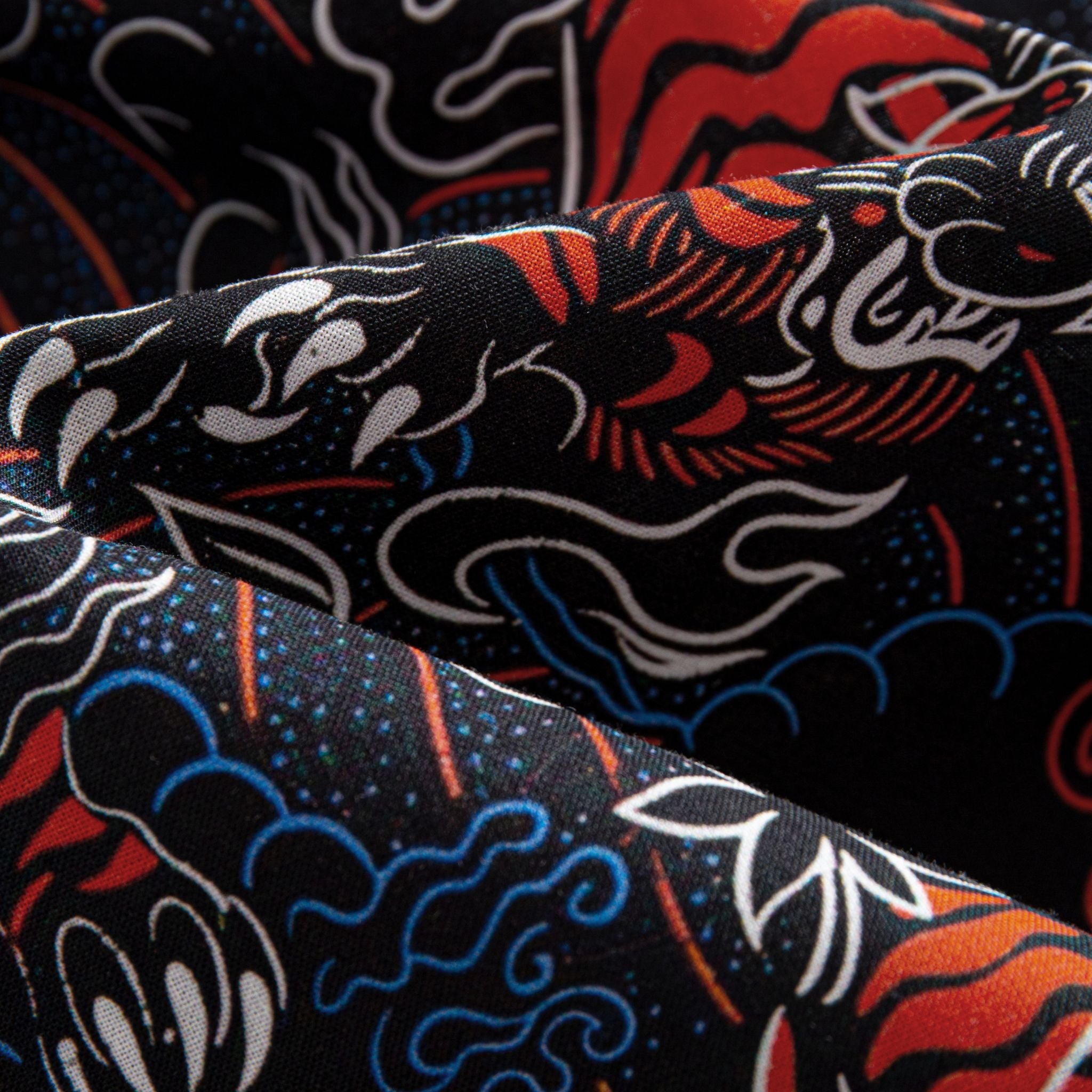 OROMEN Tiger Wave shirt – draped fabric detail showing layered red tiger blue wave and white cloud motifs on black cotton highlighting fabric texture and print depth