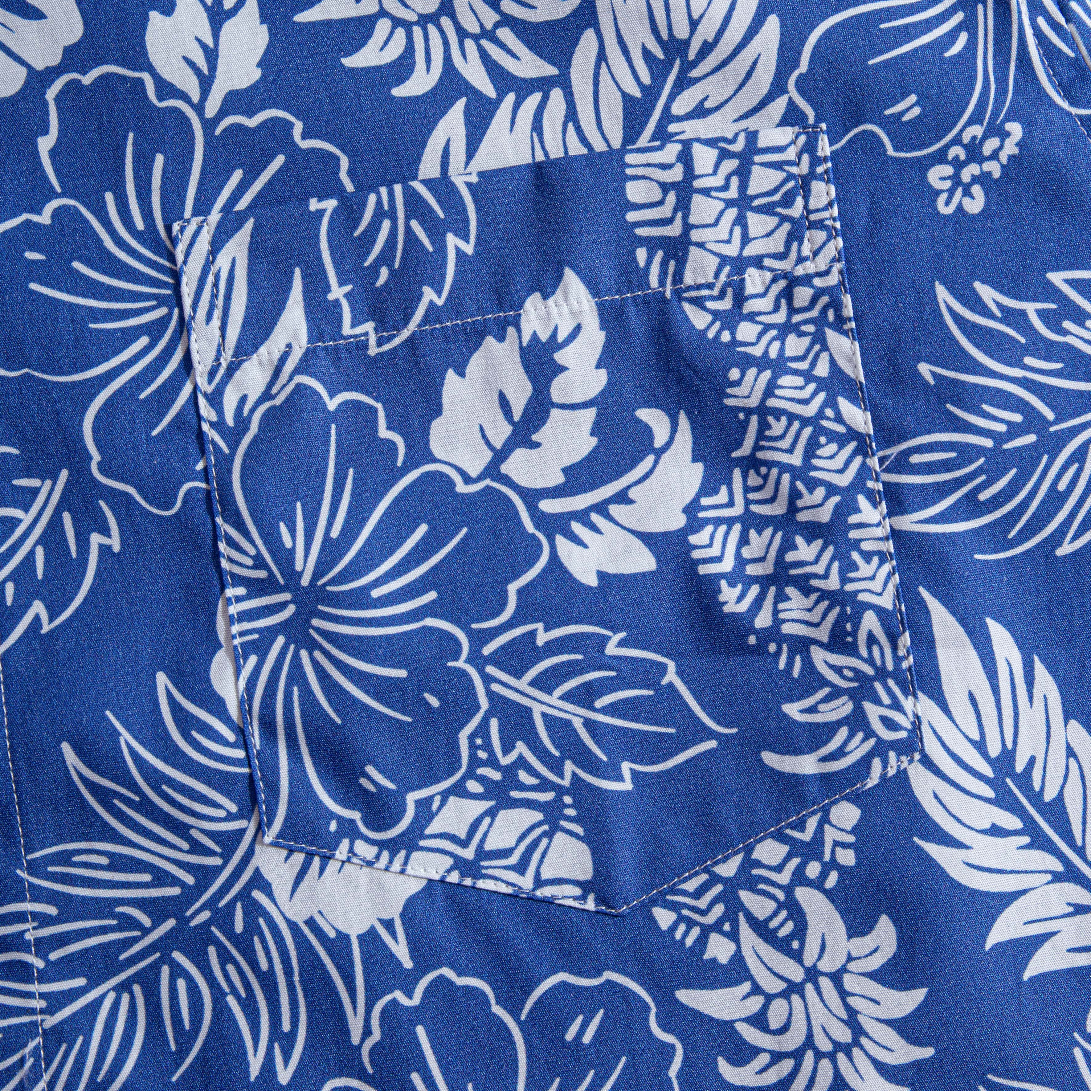 OROMEN Tropical Paradise shirt – chest pocket detail on navy blue ground with white hibiscus, pineapple and tropical leaf print, showing double-needle stitching craftsmanship