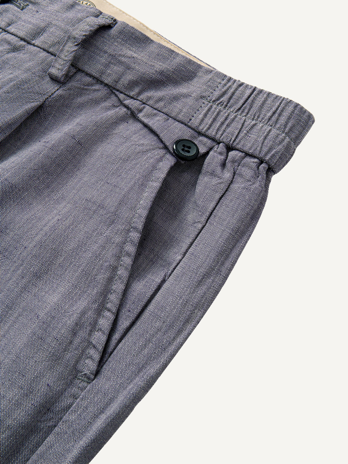 Pocket detail of OROMEN Pleated Relaxed Fit Linen Trousers showing buttoned coin pocket
