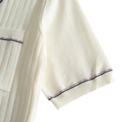 Short sleeve cuff close-up on cream knit polo, navy and rust contrast
stripe tipping, fine ribbed knit edge, clean finish – OROMEN
