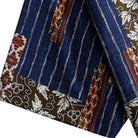 Silk Road Patchwork shirt hem detail showing indigo ikat stripe body, dark brown botanical border and ethnic geometric panels