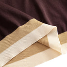 Tri-color blocked ribbed hem close-up, chocolate brown to camel
to off-white, OROMEN color-block knit polo shirt detail