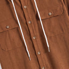 Wooden button and dual flap chest pocket detail on OROMEN rust brown hooded shirt with white drawstring